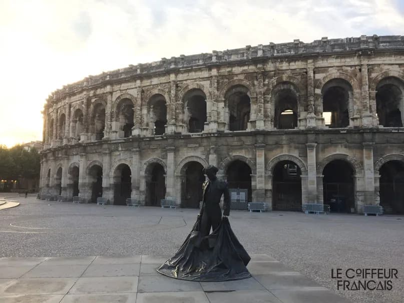 Les arènes de Nîmes au petit matin et la statue du torero sur l’esplanade, photographiées par le salon.