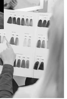 Une main désigne une mèche sur le nuancier de coloration déployé au salon.