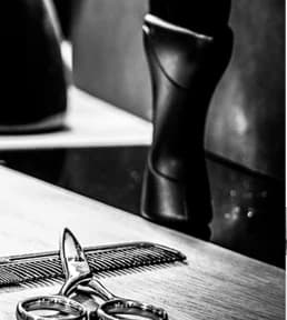 Ciseaux, peigne et sèche-cheveux posés sur le plan de travail en bois du salon.